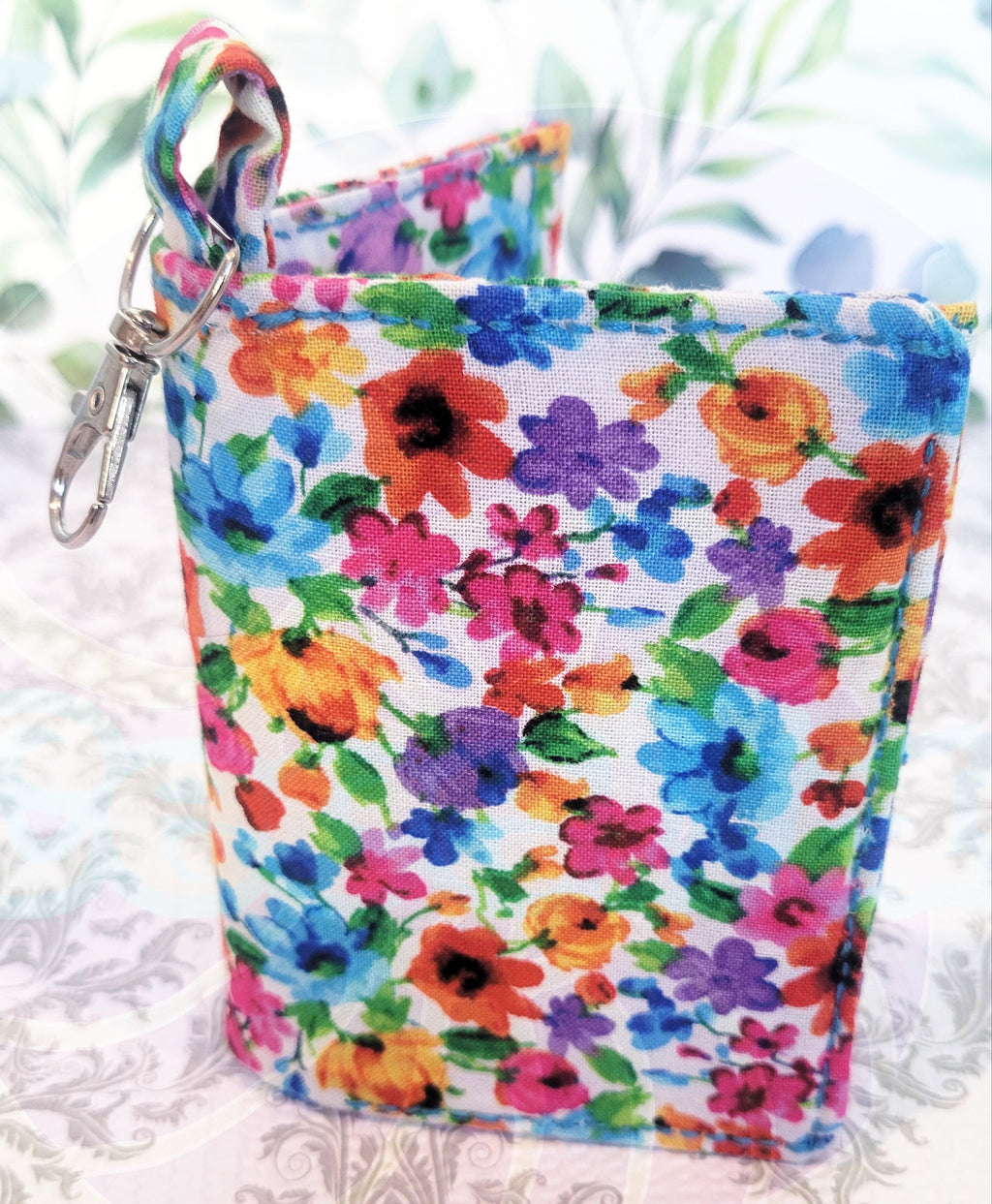 Multicolored floral-wallet pouch with a keychain on a white lace background