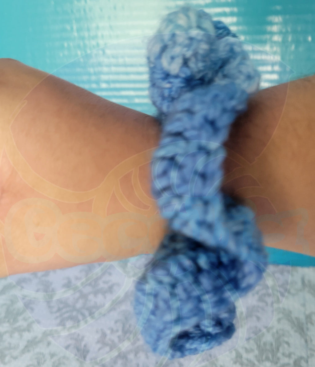 Blue gradient scrunchie on a person's wrist with a patterned background