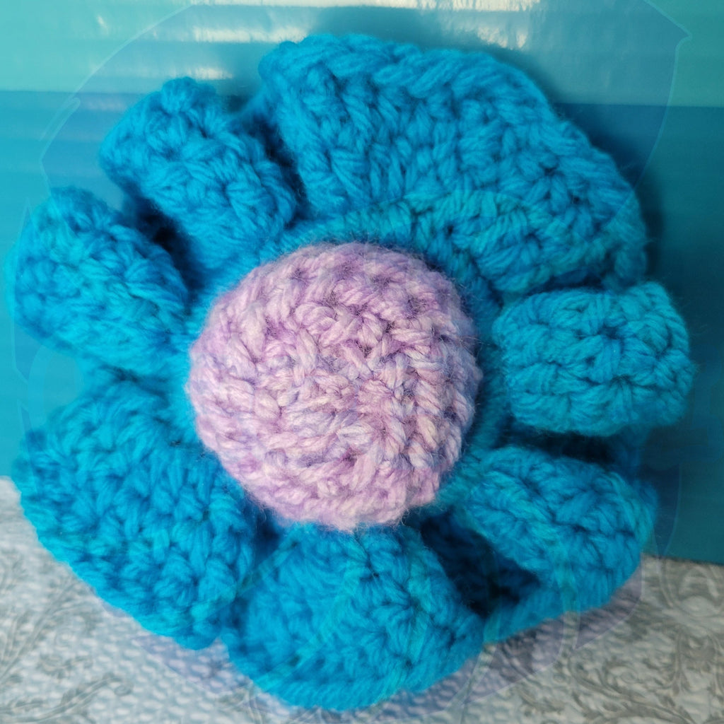 a blue crayon scrunchie on a purple ball on a textured surface with a blue background