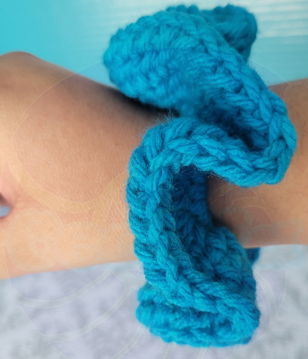 Blue crochets scrunchie on a wrist with a blurred background