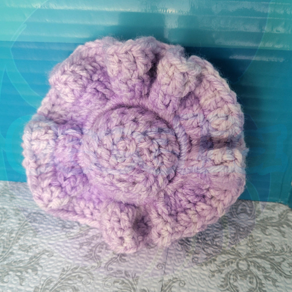 a purple scrunchie with a purple center ball  on a textured surface with a blue background