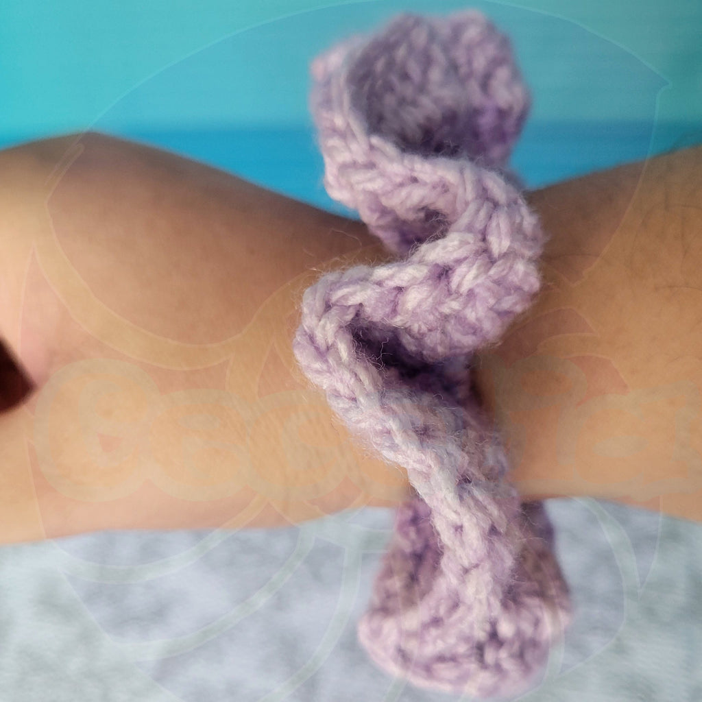 Purple crochet scrunchie on a person's arm with a blurred background
