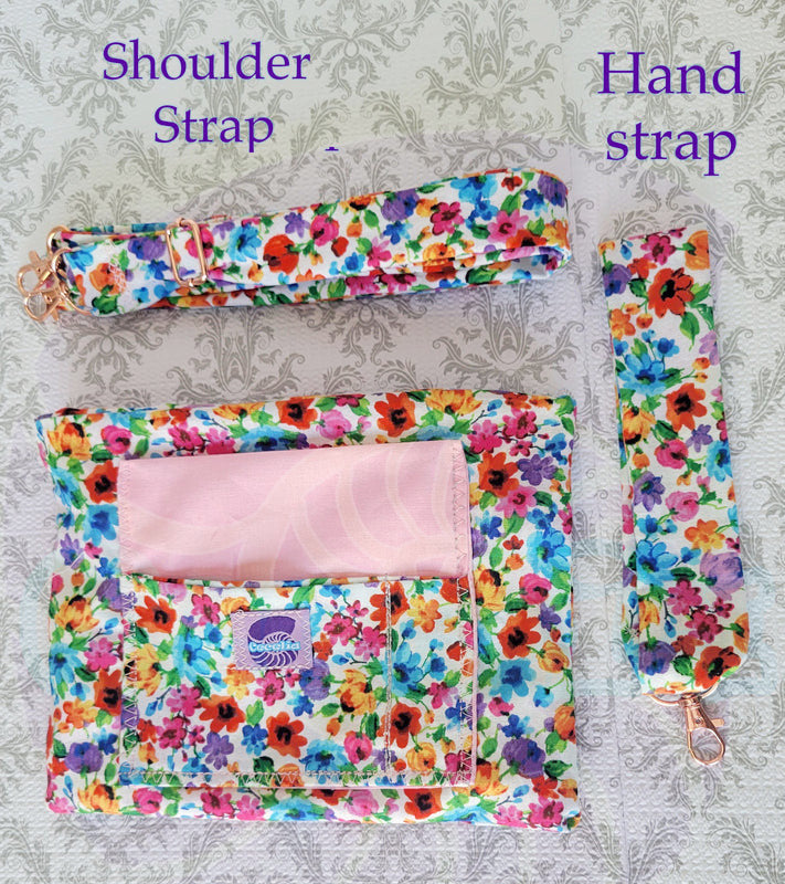 colorful Floral-patterned pouch purse in white with a light pink pocket on a textured white background. One stop of the pouch in the picture is the adjustable strap and on the right side is the hand size strap.