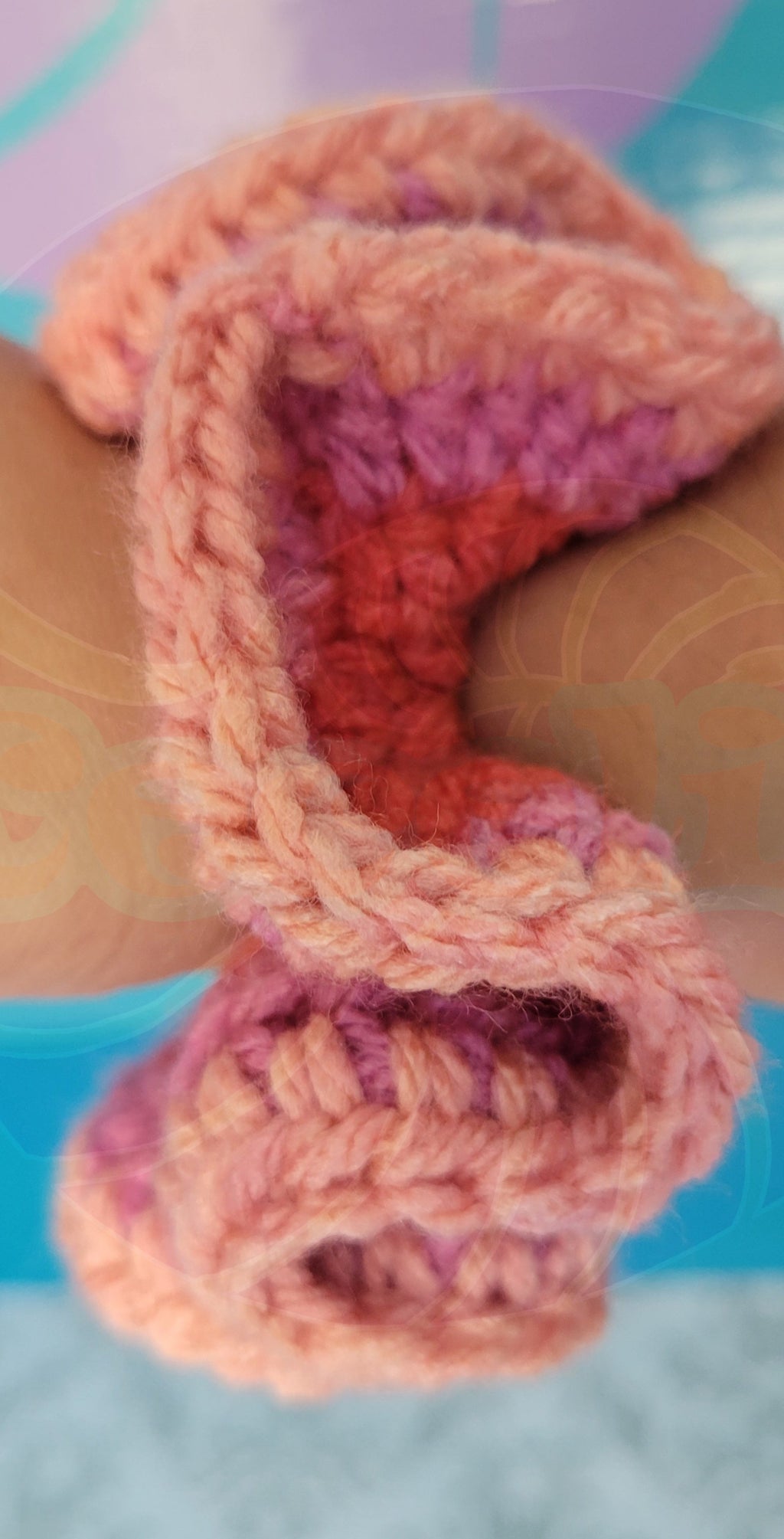 a three shades of pink scrunchie on a hand with a colorful background