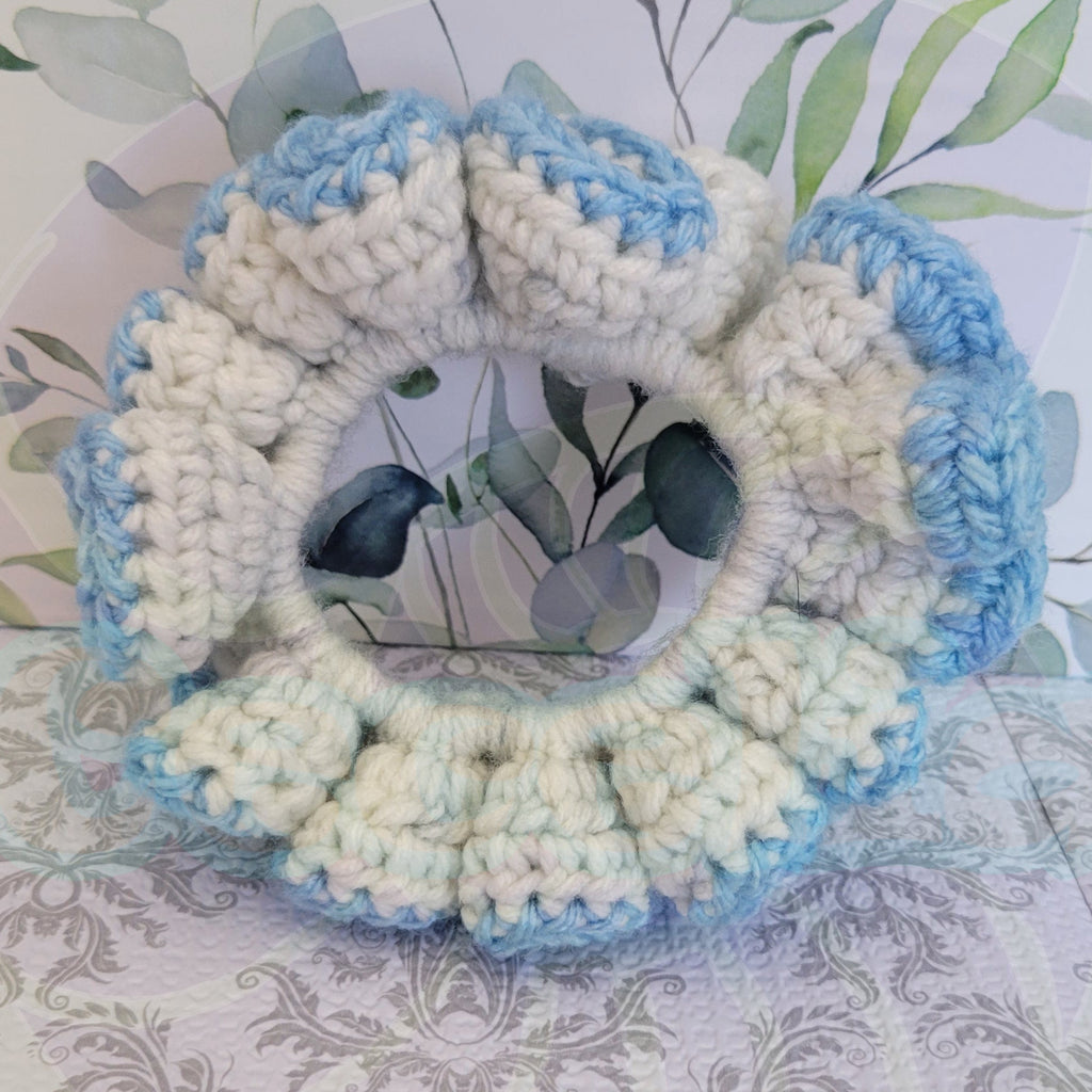 Crocheted scrunchie with blue and beige pattern on a floral background