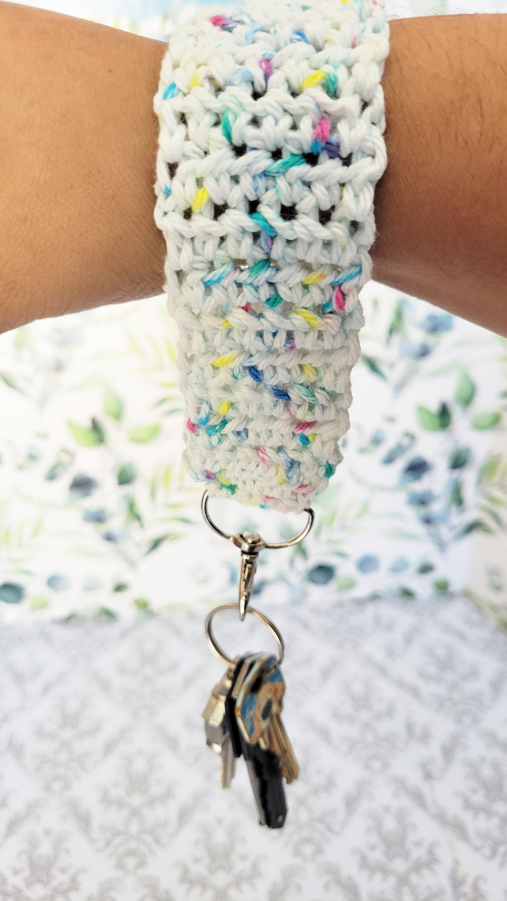 crochet wrist bracket key chain in white yarn and colorful sparkles.