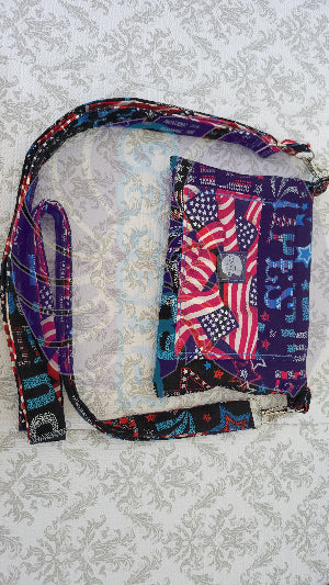 Multicolored fabric crossbody purse with American flag pattern on a textured gray background