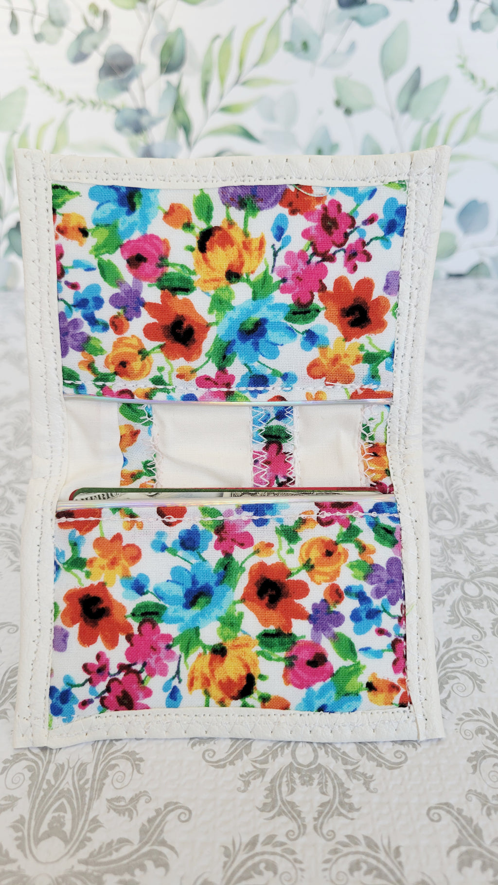 Floral-patterned white wallet on a floral background