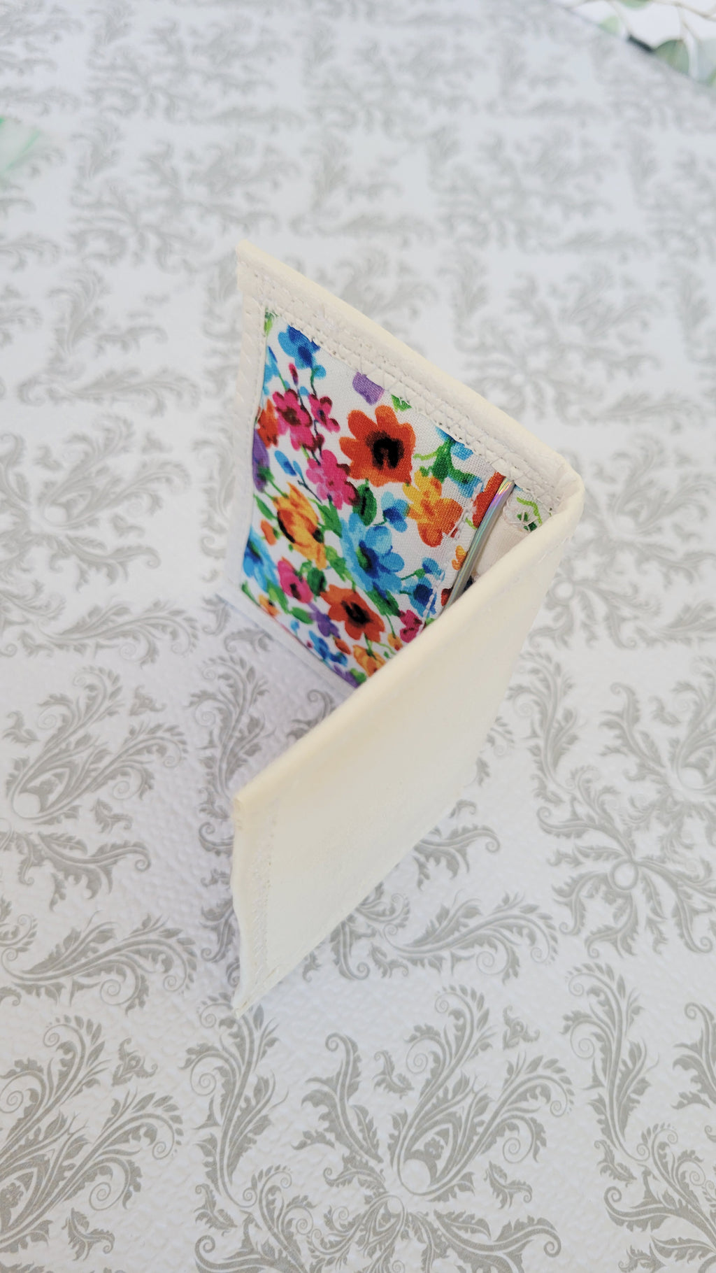 Colorful floral wallet standing in open book position on a textured white background