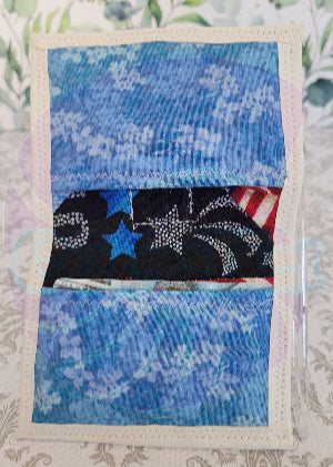 Quilted fabric square with blue floral pattern and black fabric with american flag design on a floral background