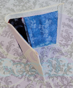 Quilted fabric wallet with blue floral pattern and black fabric with american flag design on a floral background. There are two pocket is floral blue color.