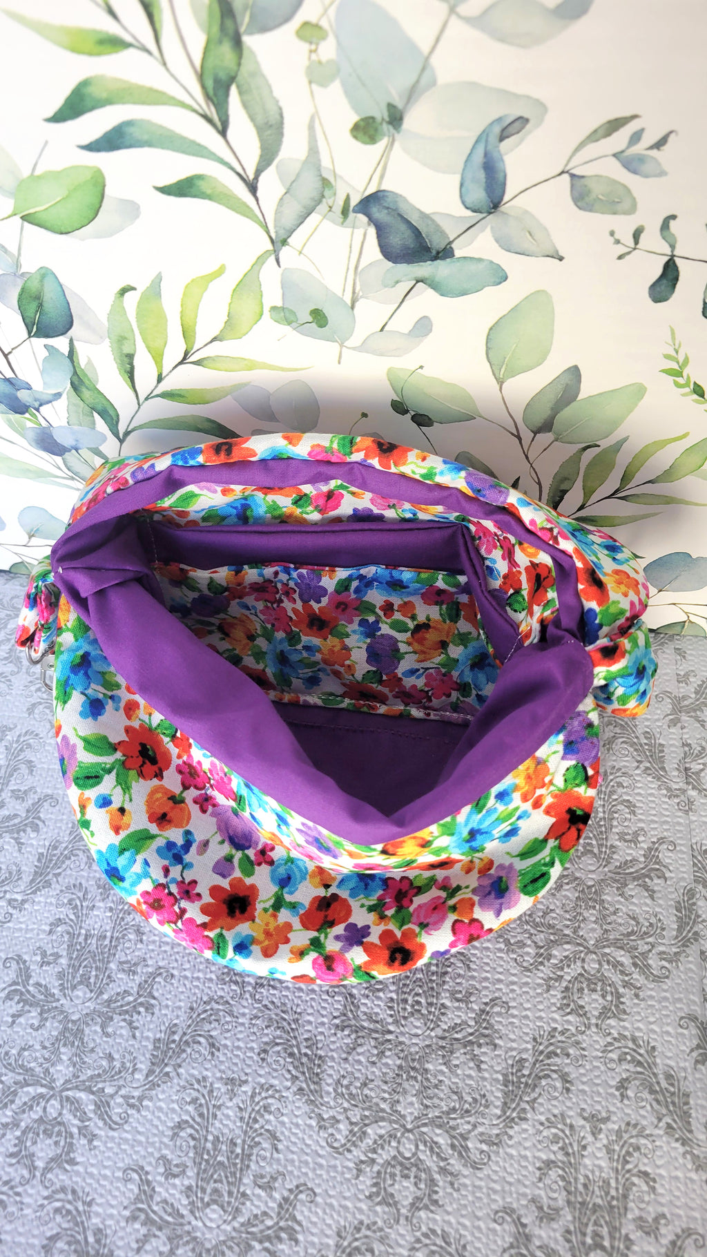 colorful Floral-patterned pouch purse in white with a purple pocket on a textured white background. Open to show it's inside colorful floral pocket.