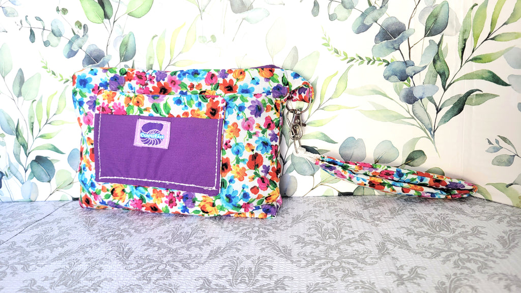 colorful Floral-patterned pouch purse in white with a purple pocket on a textured white background. 