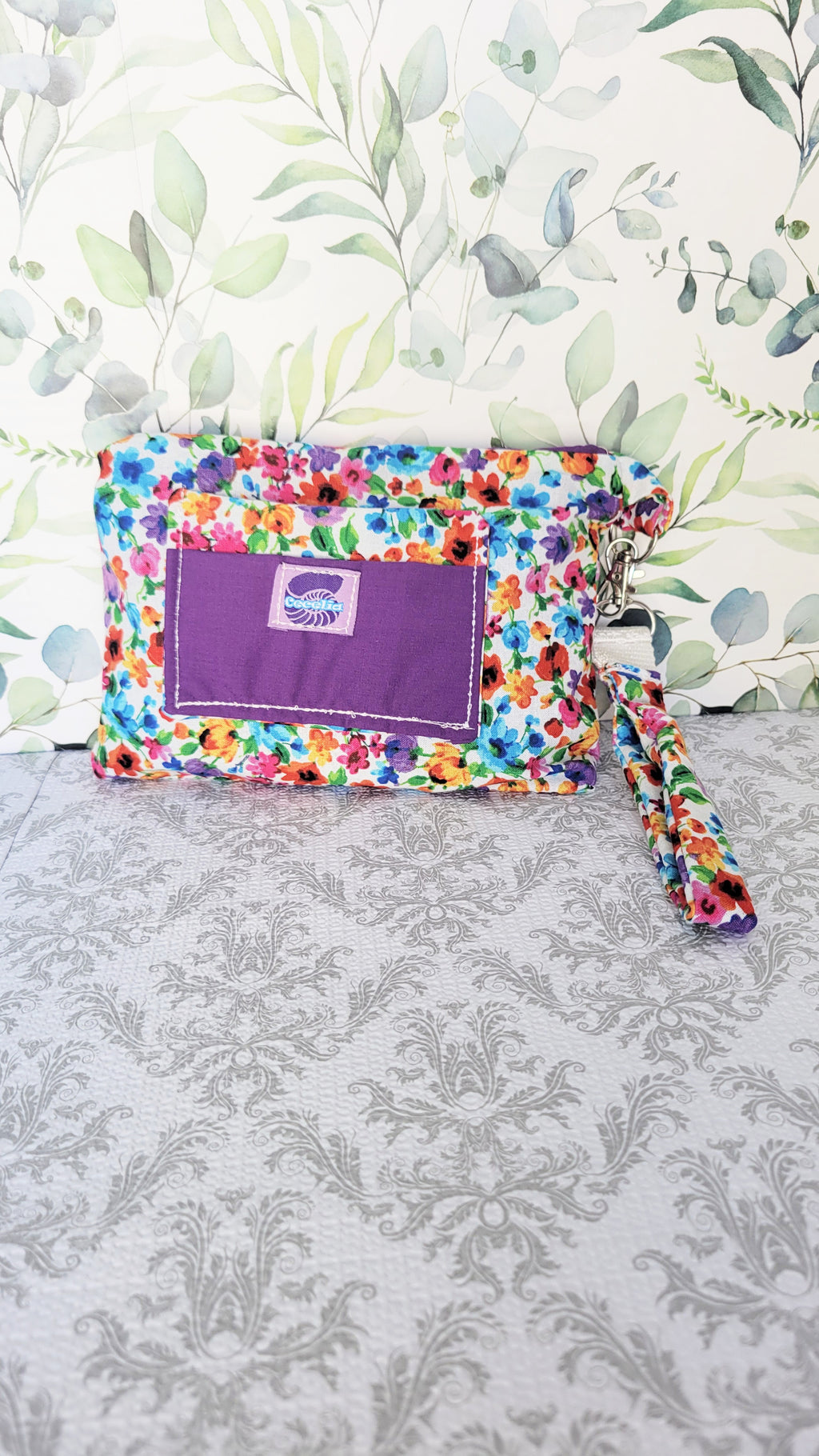 colorful Floral-patterned pouch purse in white with a purple pocket on a textured white background