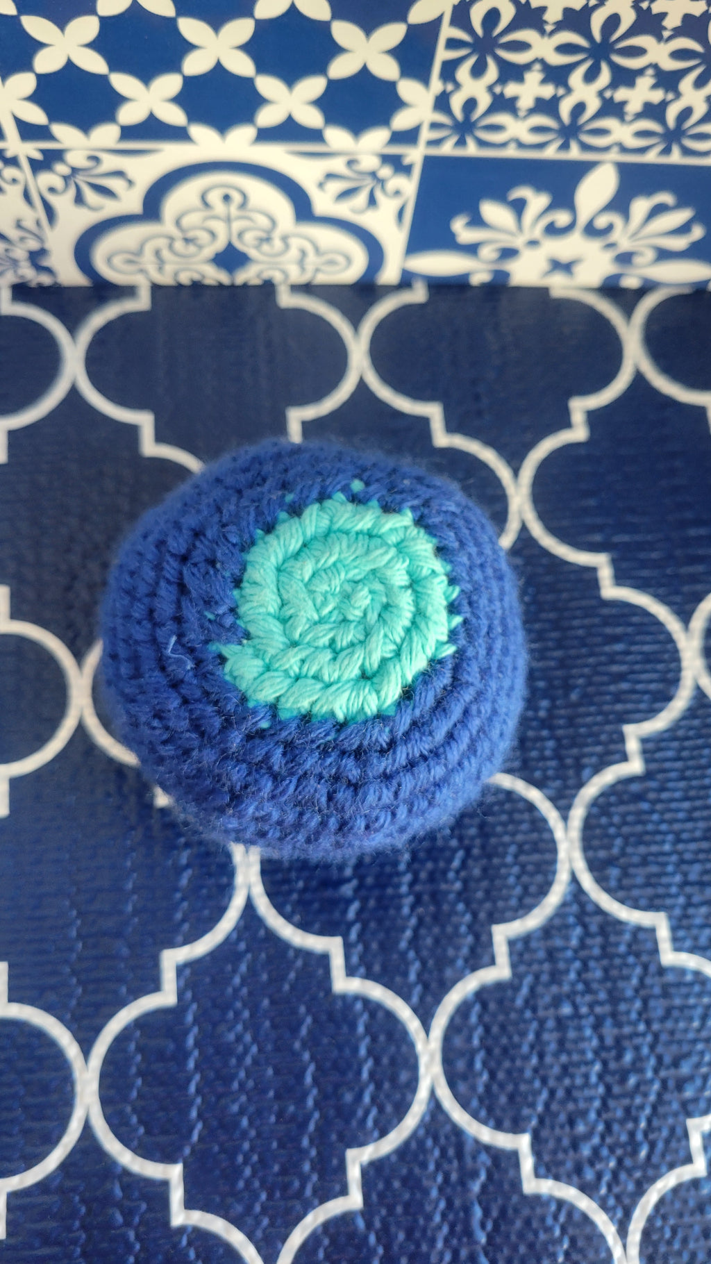 Royal Blue crocheted ball with a light blue center on a blue patterned fabric background