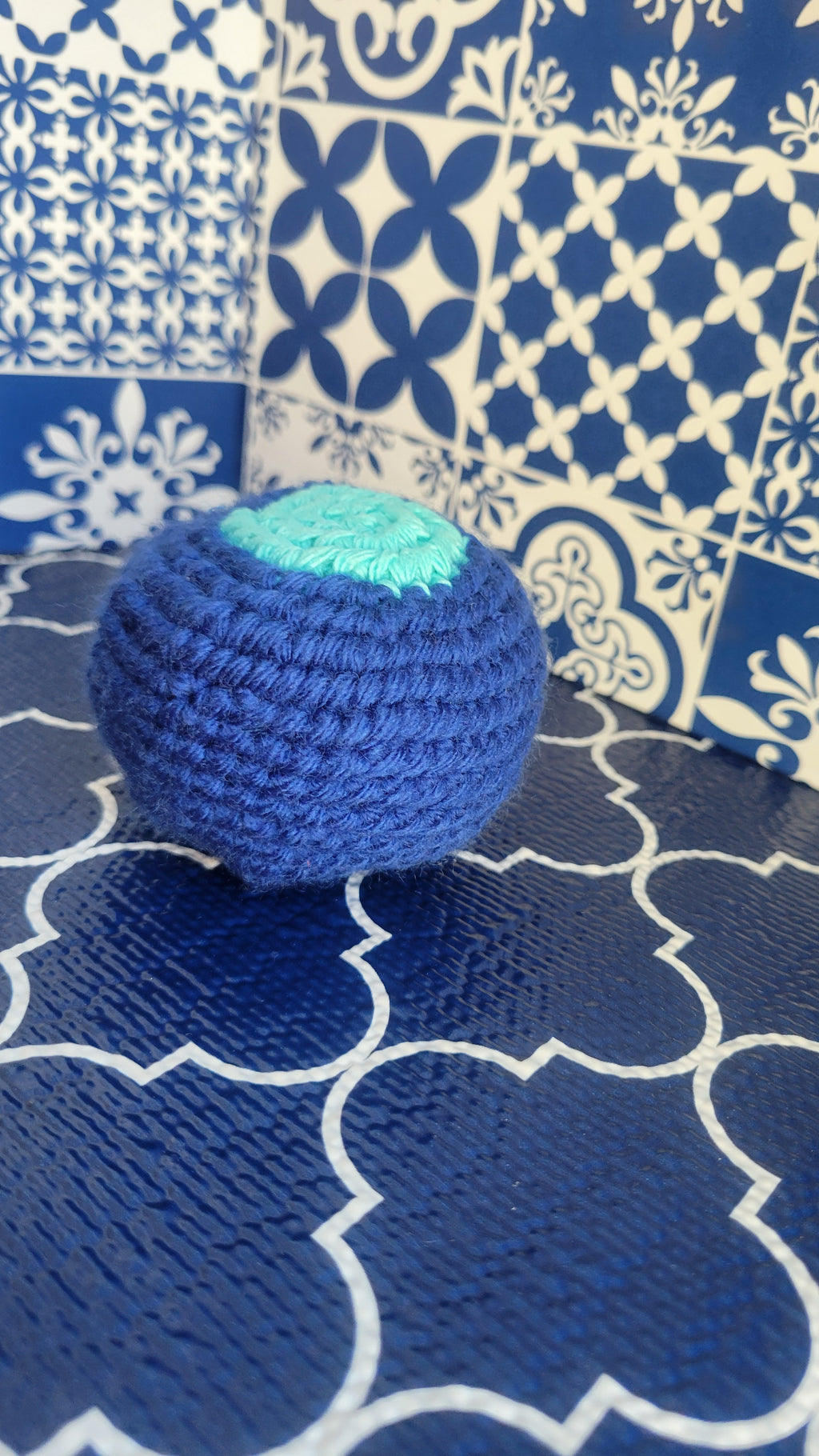 Blue cotton crochet ball on a blue patterned fabric background