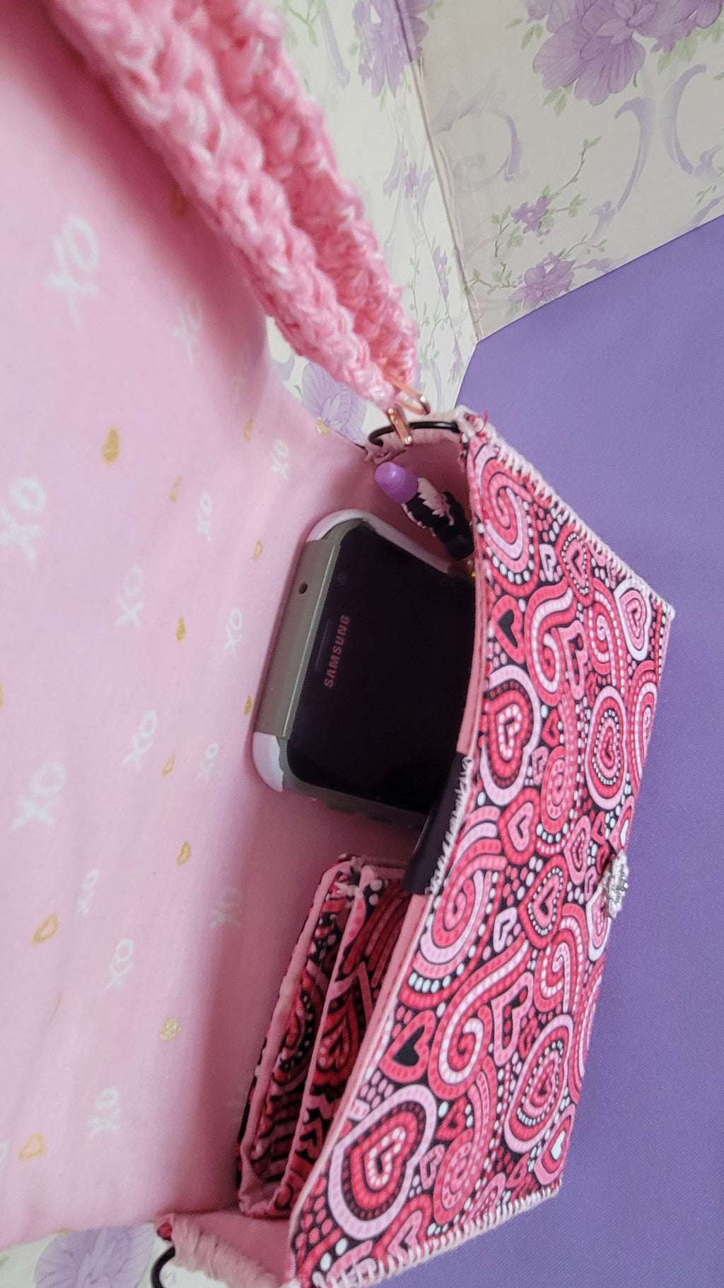 Pink Flores Clutch Purse with a ripple effect of hearts in a selection of colors pink, white, red and black. This item is open with the words xoxo and a gold heart on a light pink background pattern. inside it shows the space inside the clutch purse.