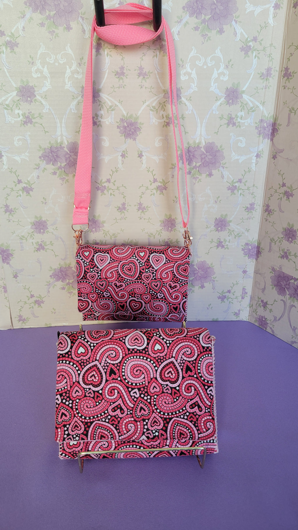 Pink Flores Clutch Purse with a ripple effect of hearts in a selection of colors pink, white, red and black. One is Hanging and the other is on a frame.