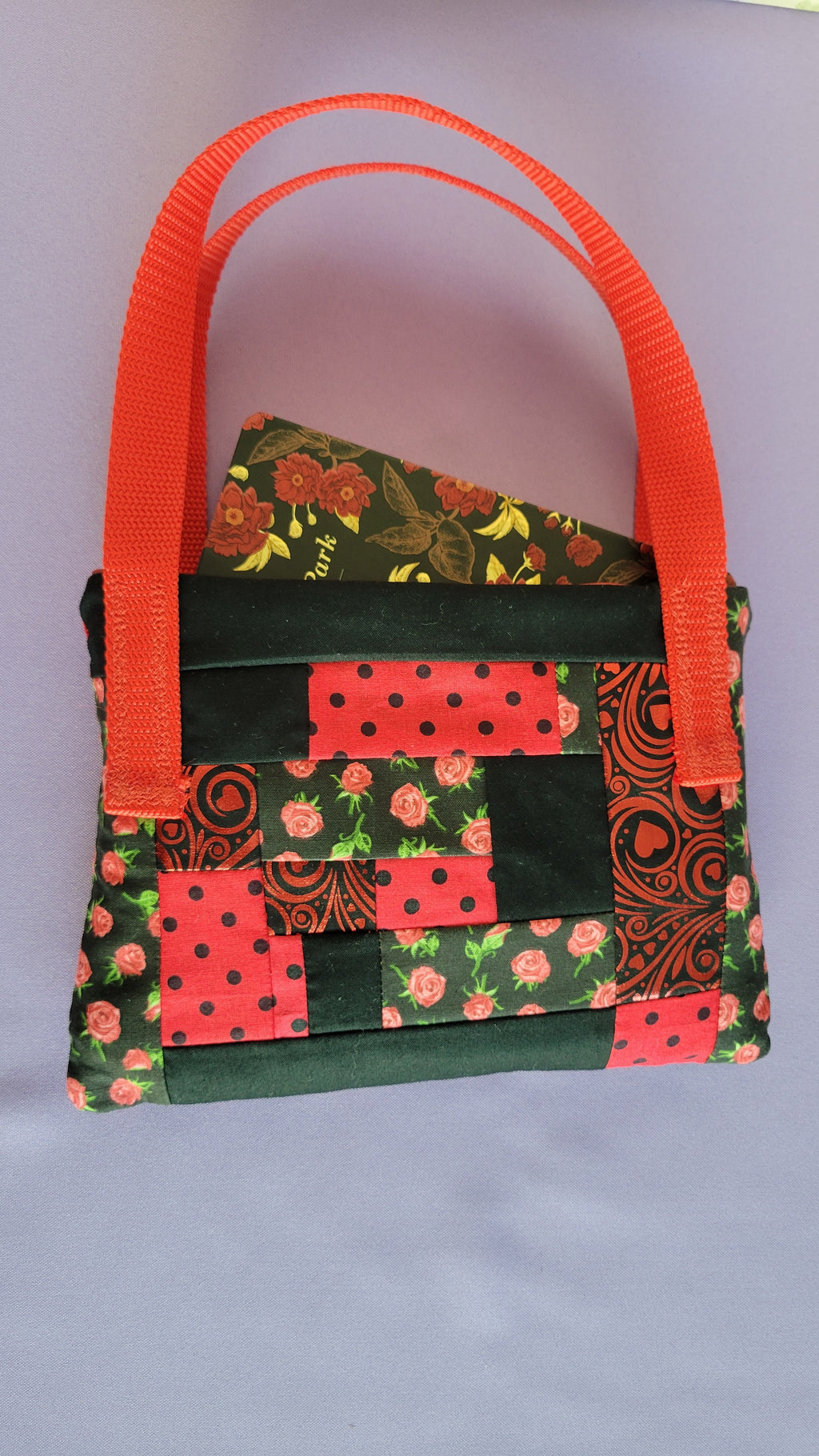 A Red Toe bag called Tracy style with two straps in red. The 5 quilt style bag has the color black., red with black polka dots, red swirls and hearts in black background, and red roses with green leaves pattern on background fabric. 

Inside of the purse is another view with the Mansfeld Park Book.