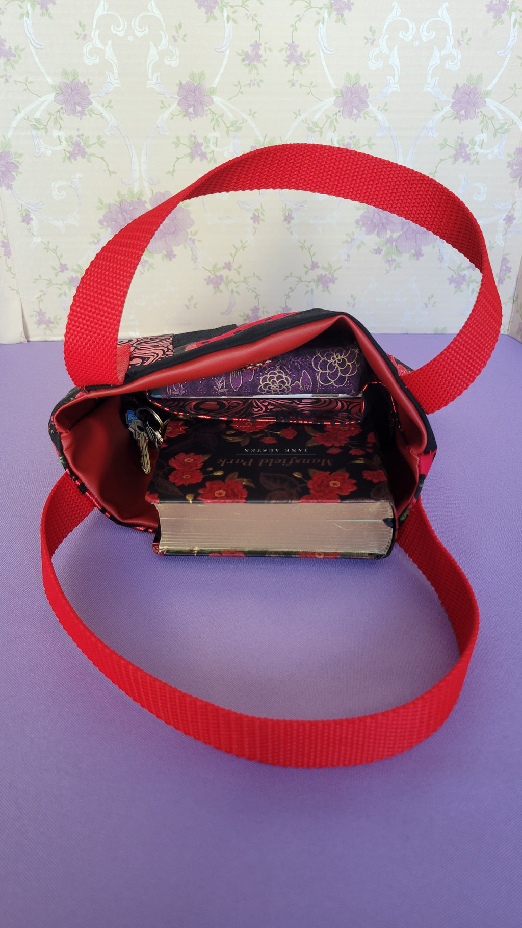 A Red Toe bag called Tracy sytle with two straps in red. Open up to show a purple wallet, mansfield pack collectable in red and keys. 