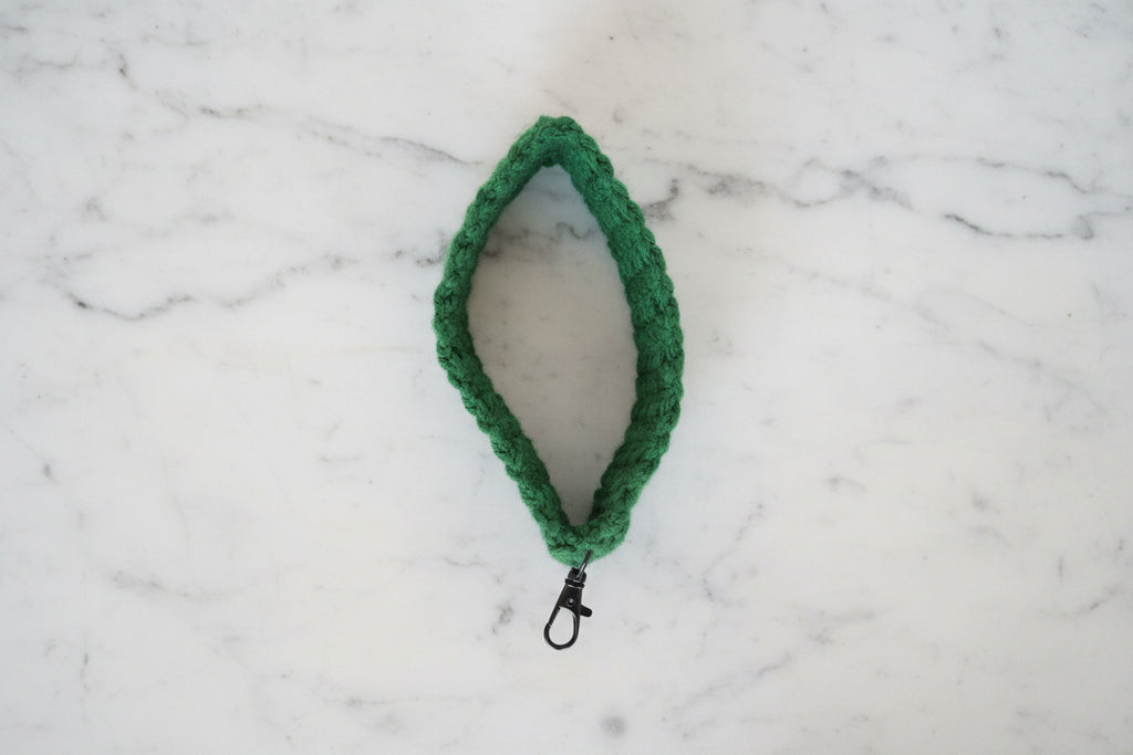 Green crochet key bracelet on a marble background.