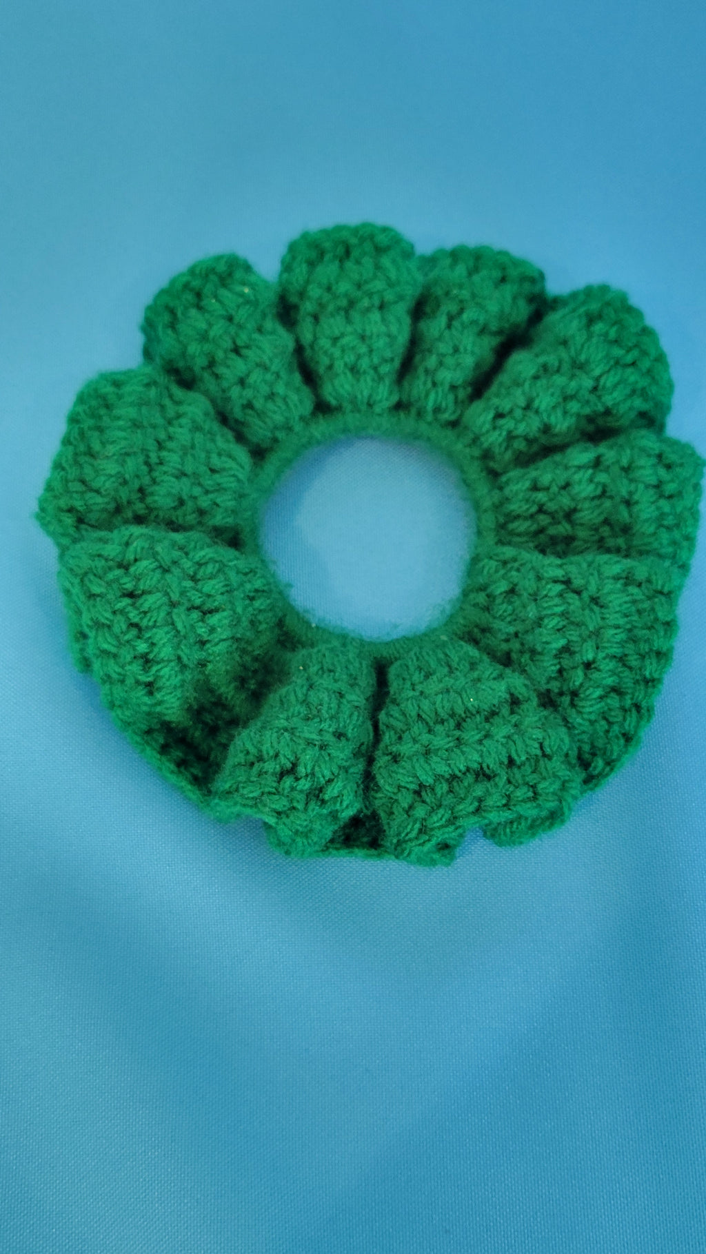Green crocheted scrunchie on a blue background