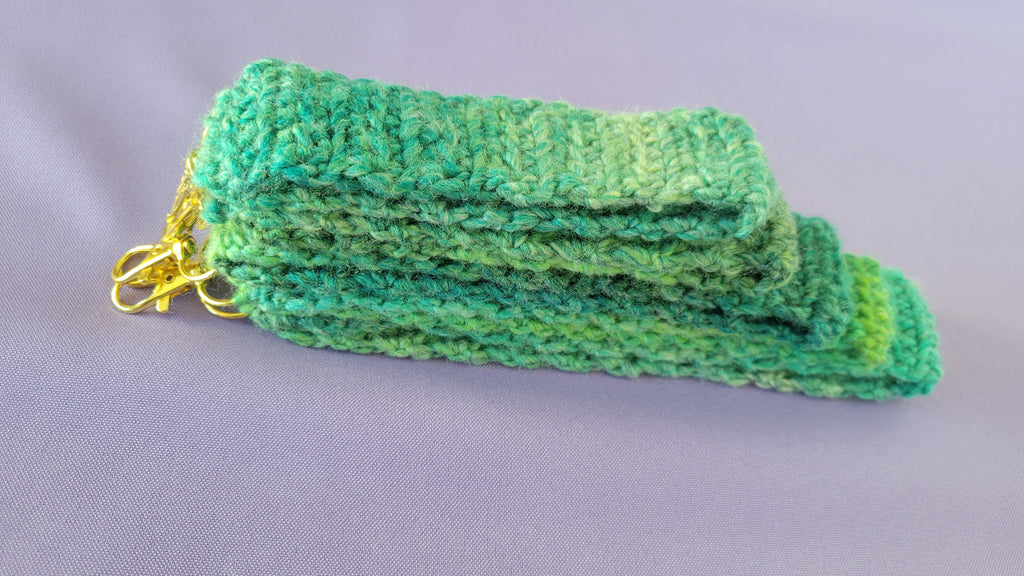 A stack of green crochet key bracelets  with a gold hook attach. The size go from 5- 9 inches.