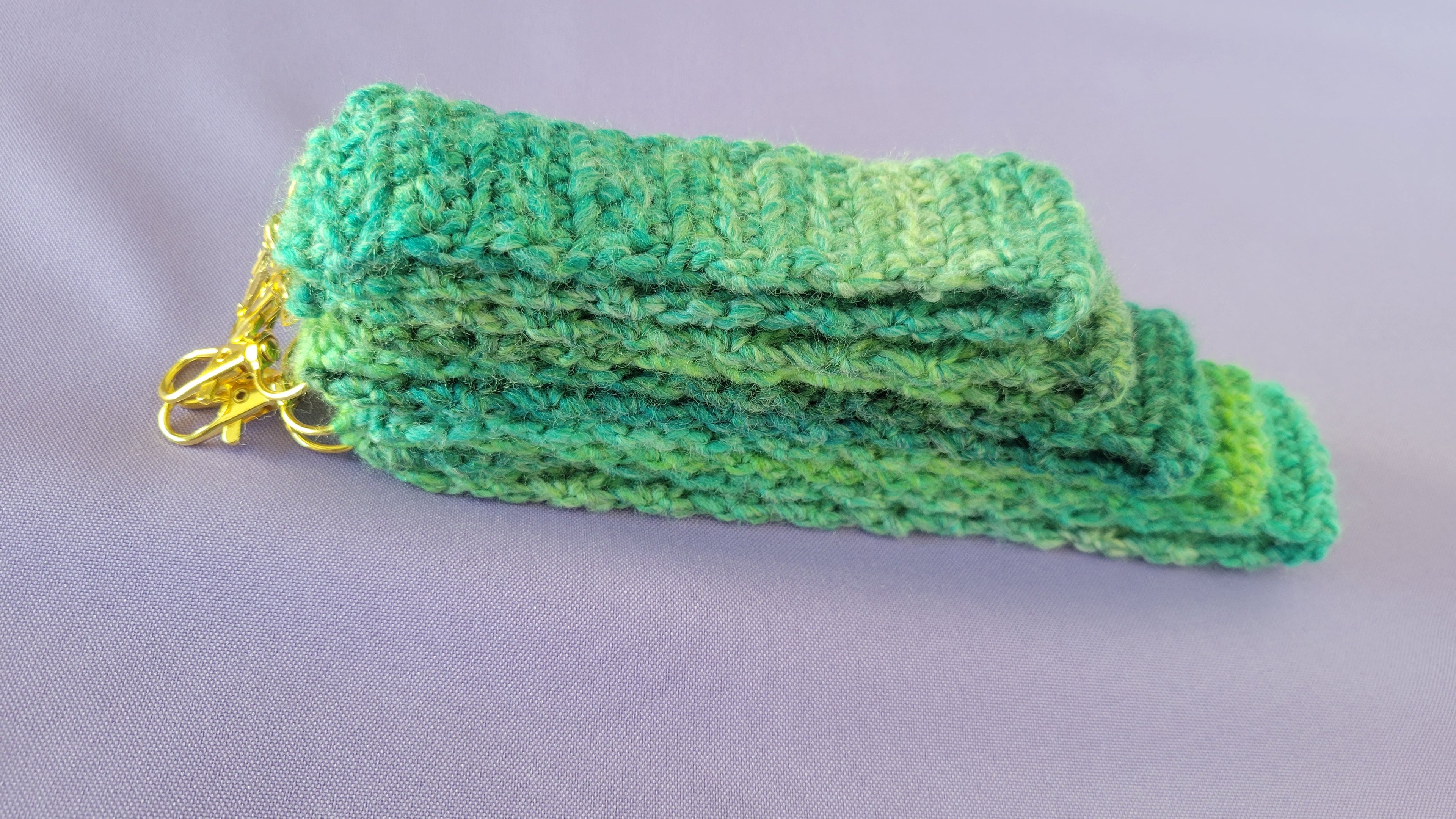 A stack of green crochet key bracelets  with a gold hook attach. The size go from 5- 9 inches.