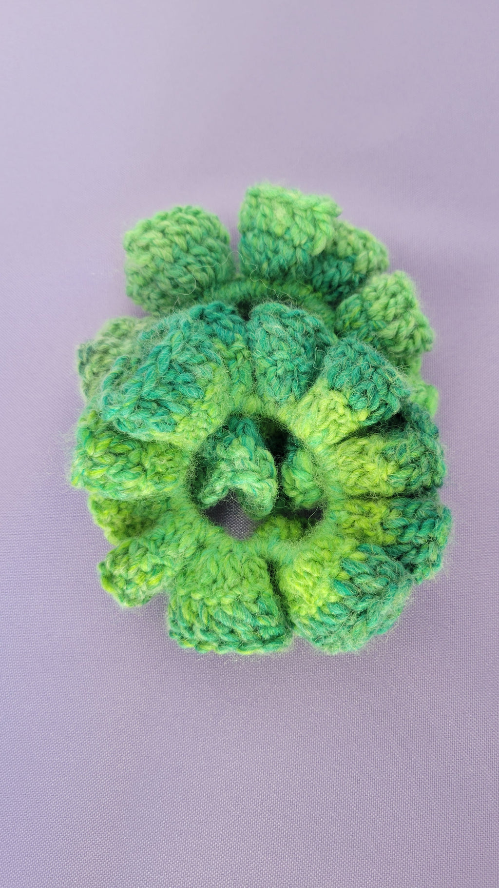 Green crocheted scrunchies on a purple background