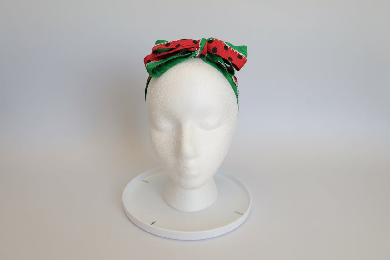 Watermelon theme hairband in a bow on a mannequin head. 